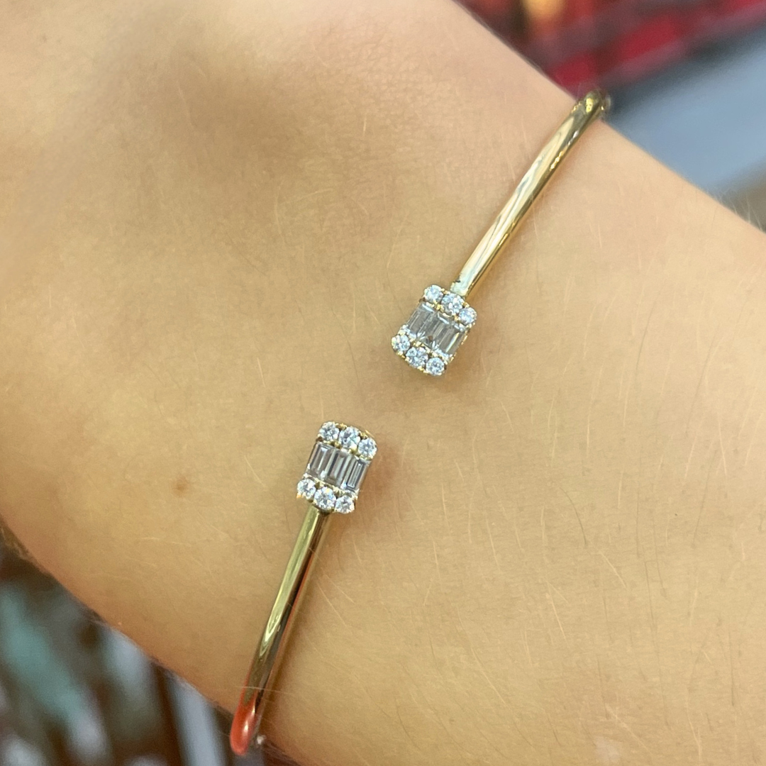 Gold bracelet with diamonds on a wrist against a blurred background