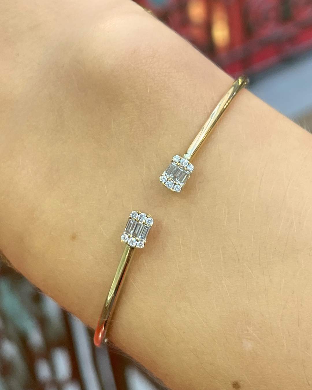 Gold bracelet with diamonds on a wrist against a blurred background